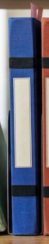 Digitally rendered: the spine of an ultramarine blue cloth notebook on a wooden shelf.